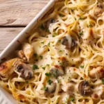 Chicken Tetrazzini in a casserole dish with melted cheese and herbs