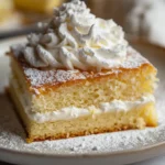 Slice of fluffy lemon cake with whipped cream and powdered sugar