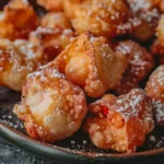 Deep fried strawberry cheesecake stuffed wonton bites dusted with powdered sugar