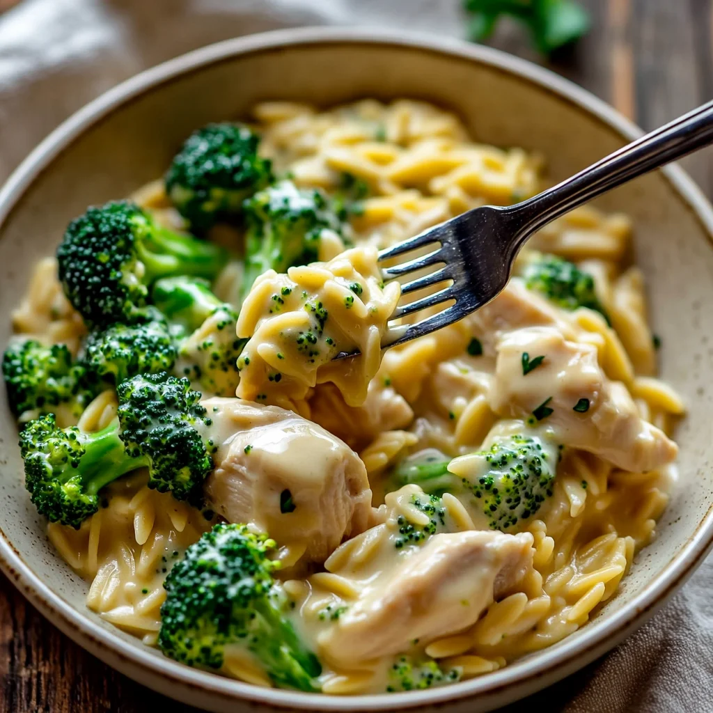 Creamy chicken broccoli orzo in a white ceramic dish with glossy sauce coating tender chicken and vibrant green broccoli